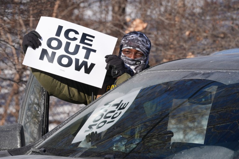 Anti-ICE protestor waves sign saying 