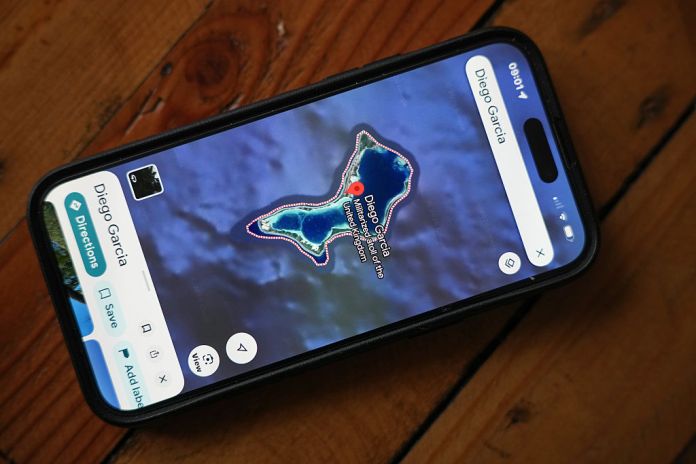 A phone shows the position of Island of Diego Garcia on Google maps. (illustration by Christopher Furlong/Getty Images)