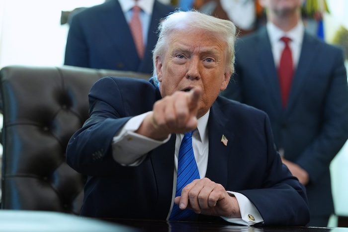 President Donald Trump points figure toward camera in Oval Office.
