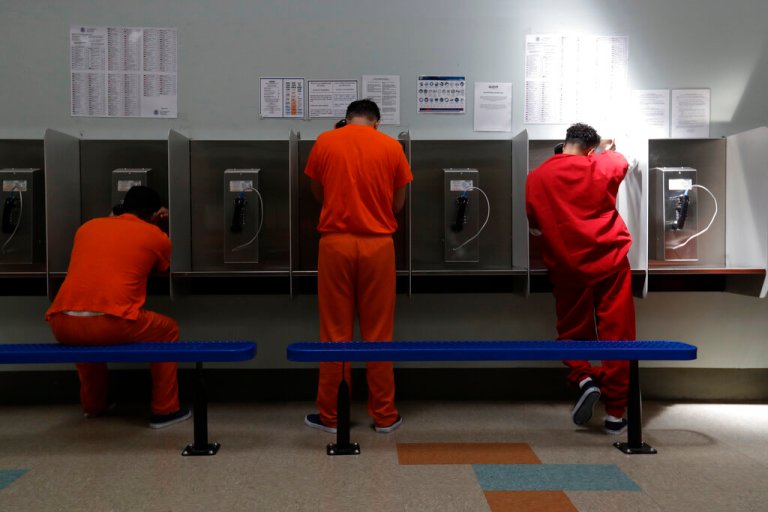 Detainees talk on telephones at the Adelanto ICE Processing Center in Adelanto, Calif., Aug. 28, 2019. A federal appeals court on Tuesday, April 26, 2022, agreed to reconsider a ruling that rejected the state’s first-in-the-nation ban on for-profit private prisons and immigration detention facilities. (AP Photo/Chris Carlson, File)