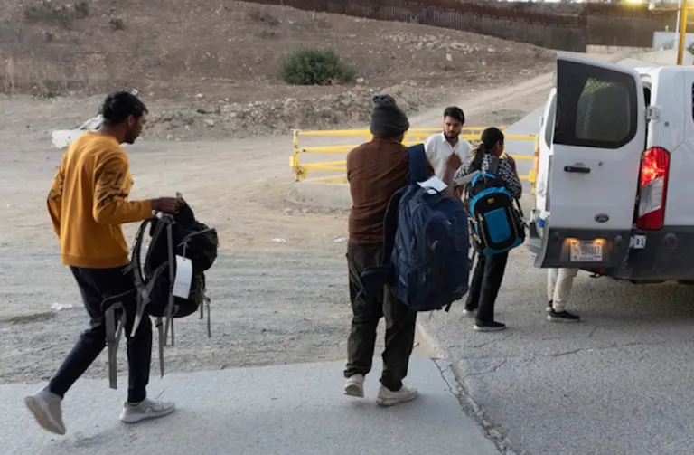 Migrants make their way to a Border Patrol van after crossing illegally and waiting to apply for asylum between two border walls separating Mexico and the United States, Tuesday, Jan. 21, 2025, in San Diego. (AP Photo/Gregory Bull)