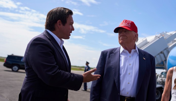 President Donald Trump listens as Gov. Ron DeSantis, R-Fla., speaks with reporters after arriving at Dade-Collier Training and Transition Airport, Tuesday, July 1, 2025, in Ochopee, Fla. (AP Photo/Evan Vucci)