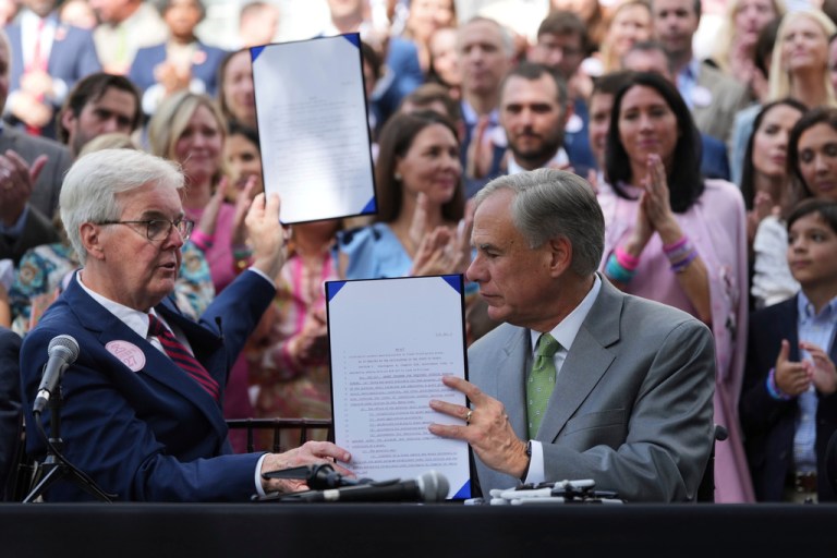 Gov. Greg Abbott, right, and Texas Lt. Gov. Dan Patrick, left, are joined by parents and family of children who died at Camp Mystic as he signs camp safety bills, Friday, Sept. 5, 2025, in Austin, Texas. (AP Photo/Eric Gay)
