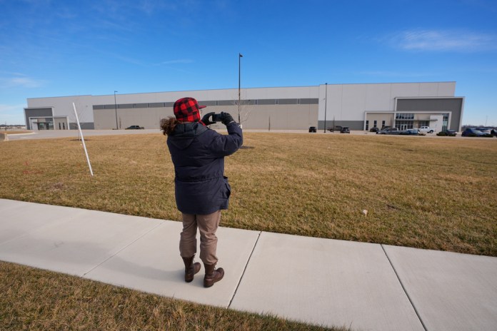 A man takes photos of a warehouse as federal officials tour the facility to consider repurposing it as an ICE detention facility Thursday, Jan. 15, 2026, in Belton, Mo. (AP Photo/Charlie Riedel)