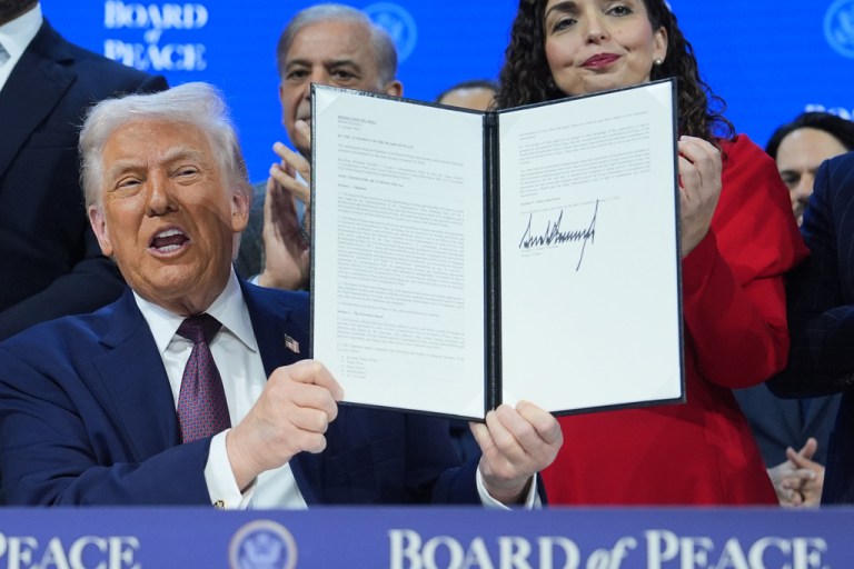 President Donald Trump holds up a signed Board of Peace charter during the Annual Meeting of the World Economic Forum in Davos, Switzerland, Thursday, Jan. 22, 2026. (AP Photo/Evan Vucci)