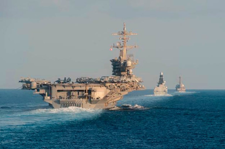 The aircraft carrier USS Abraham Lincoln, the air-defense destroyer HMS Defender, and the guided-missile destroyer USS Farragut transit the Strait of Hormuz.