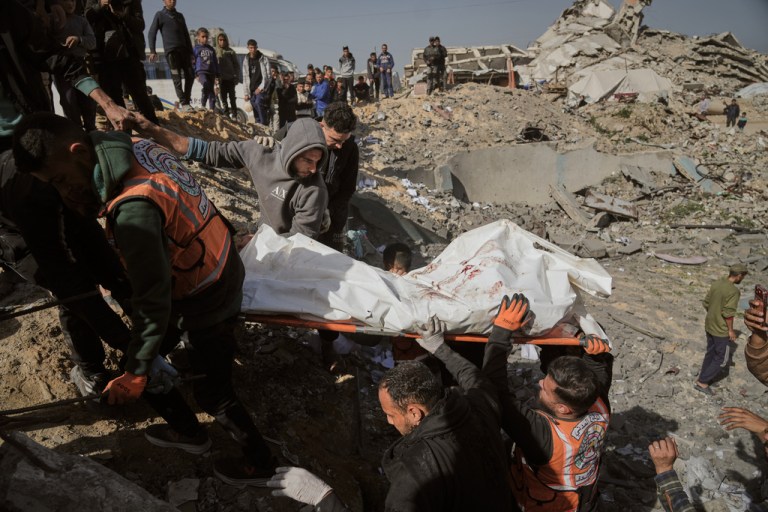 Palestinians carry a body from the rubble of police station after it was targeted by an Israeli army strike in Gaza City