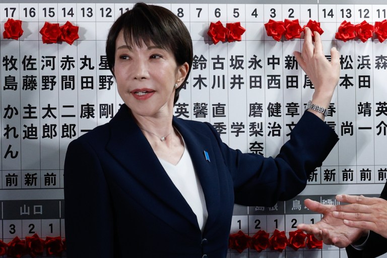 Takaichi poses with a board tracking election victories