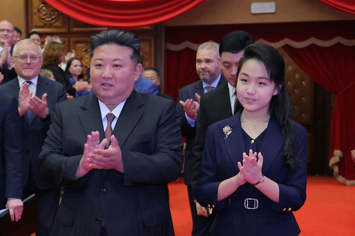 Kim Ju-Ae stands in a place of considerable importance at the side of her father