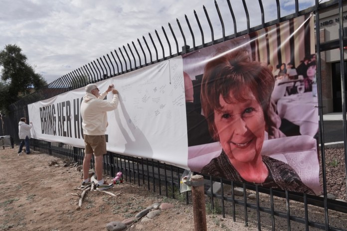 A man signs a banner supporting Nancy Guthrie