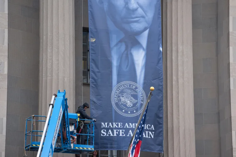 A banner showing President Donald Trump is hung from the Department of Justice