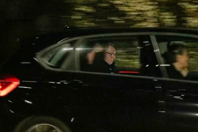 Mandelson is seen in the backseat of a car leaving a London police station