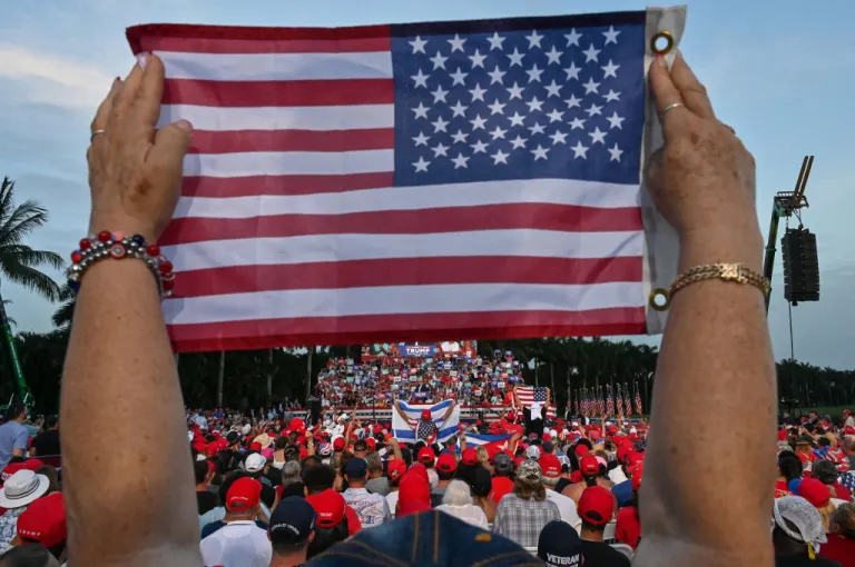 A person holds up a US flag as former US President and Republican presidential candidate Donald Trump speaks during a rally in Doral, Florida, on July 9, 2024. (Photo by GIORGIO VIERA / AFP) (Photo by GIORGIO VIERA/AFP via Getty Images)