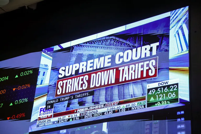 A television broadcasts news about the Supreme Court striking down President Trump's global tariffs on the floor of the New York Stock Exchange (NYSE) in New York, US, on Friday, Feb. 20, 2026. The US Supreme Court struck down Trump's sweeping global tariffs, undercutting his signature economic policy and delivering his biggest legal defeat since he returned to the White House. Photographer: Michael Nagle/Bloomberg via Getty Images