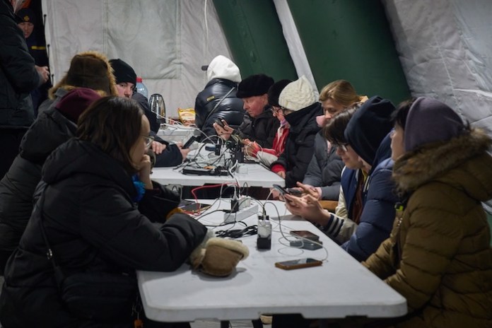 Local residents warm up and charge their batteries inside an emergency tent in Kyiv, Ukraine, Wednesday, Jan. 21, 2026, following Russia's regular air attacks on the country's energy system that leave residents without power, water and heating. (AP Photo/Efrem Lukatsky)