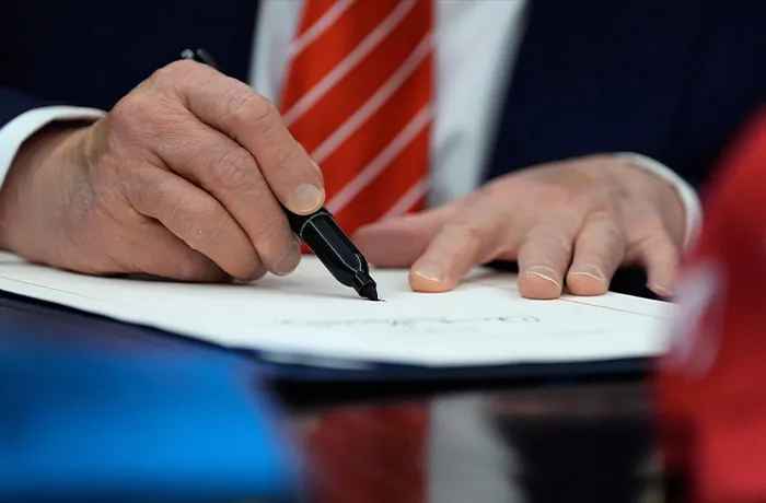 President Donald Trump signs a spending bill that ends a partial shutdown of the federal government in the Oval Office on Feb. 3. (Alex Brandon/AP)