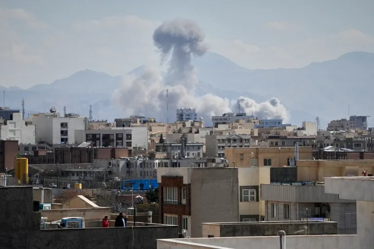 People watch from a rooftop as a plume of smoke rises after a strike in Tehran, Iran, Sunday, March 1, 2026. (AP Photo/Vahid Salemi)