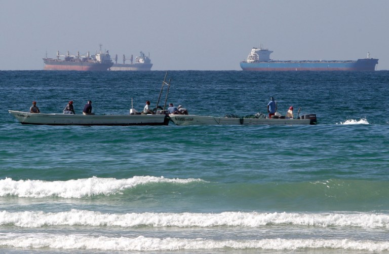 Fishermen work in front of oil tankers south of the Strait of Hormuz.