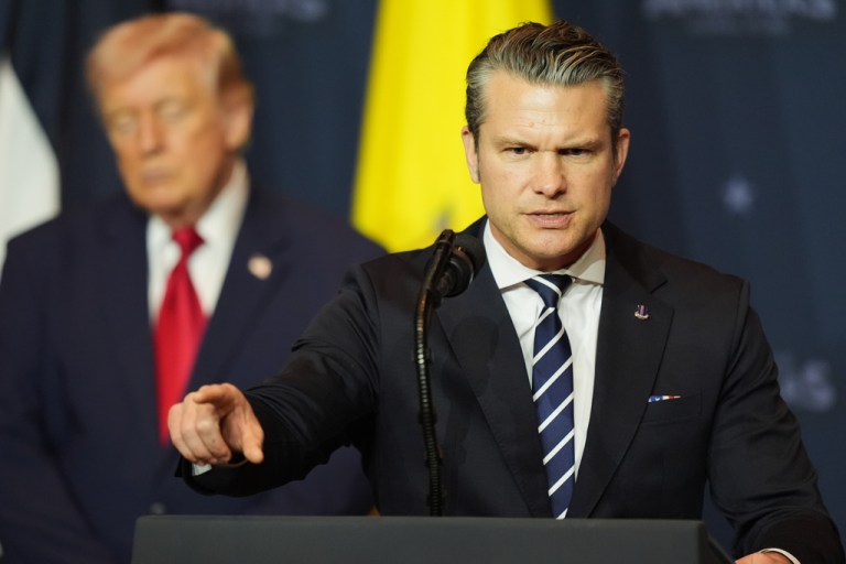 Defense Secretary Pete Hegseth speaks while President Donald Trump, left, listens at the Shield of the Americas Summit.
