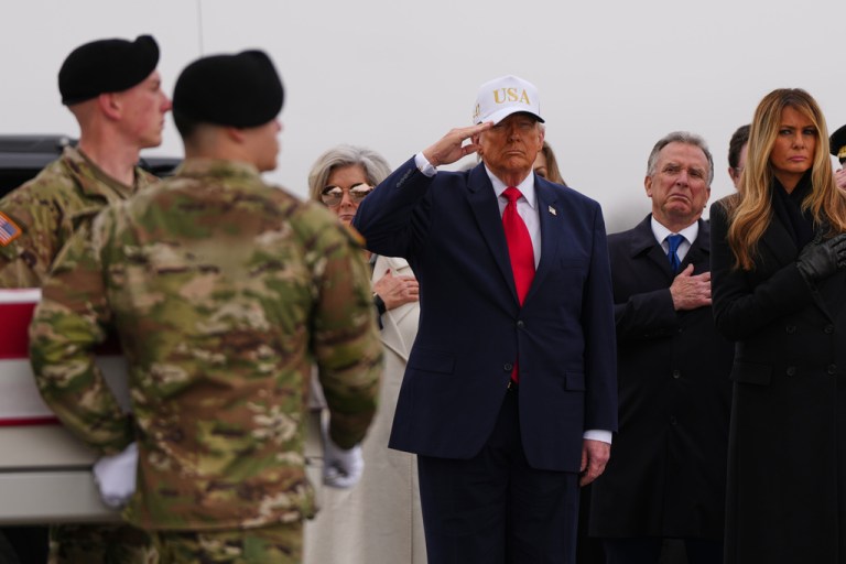 President Donald Trump salutes as an Army carry team moves the flag-draped transfer case containing the remains of six U.S. service members.
