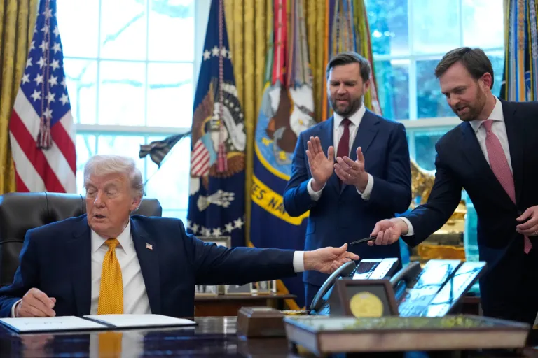 President Donald Trump hands a pen to Federal Trade Commission chairman Andrew Ferguson after he signed an executive order regarding a task force on fraud in the Oval Office of the White House, Monday, March 16, 2026, in Washington, as Vice President JD Vance applauds. (AP Photo/Julia Demaree Nikhinson)