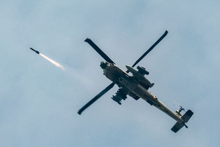 An Israeli Air Force AH-64 Apache attack helicopter fires rockets while flying along the border between northern Israel and southern Lebanon on March 18, 2026. The Israeli military said it planned to strike bridges and crossings over the Litani River in southern Lebanon on March 18 to disrupt what it said were Hezbollah arms-smuggling routes. Lebanon was drawn into the Middle East war on March 2 when militant group Hezbollah launched rockets into Israel to avenge the killing of Iran's supreme leader. (Photo by Jalaa MAREY / AFP via Getty Images) /