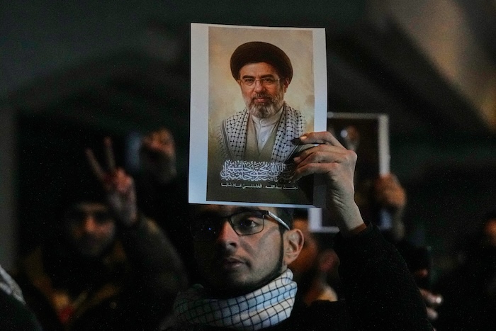 Iraqis hold a portrait of the new Iranian supreme leader, Ayatollah Mojtaba Khamenei.