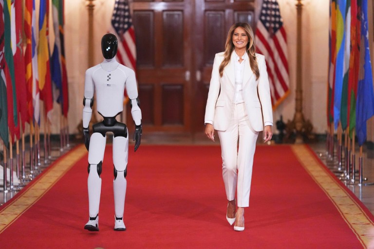 First lady Melania Trump arrives, accompanied by a robot, to attend the 