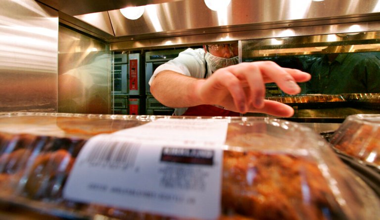 Costco employee Michael Hicks reaches for a container of rotisserie chicken to date-stamp at a Seattle store Thursday, May 29, 2008. (AP Photo/Elaine Thompson)
