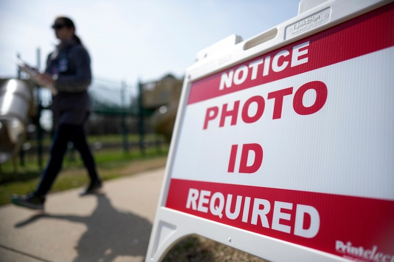 A Super Tuesday voter walks past a sign requiring a photo ID at a polling location.