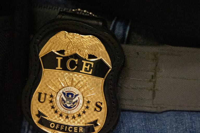 A federal agent wears an Immigration and Customs Enforcement badge