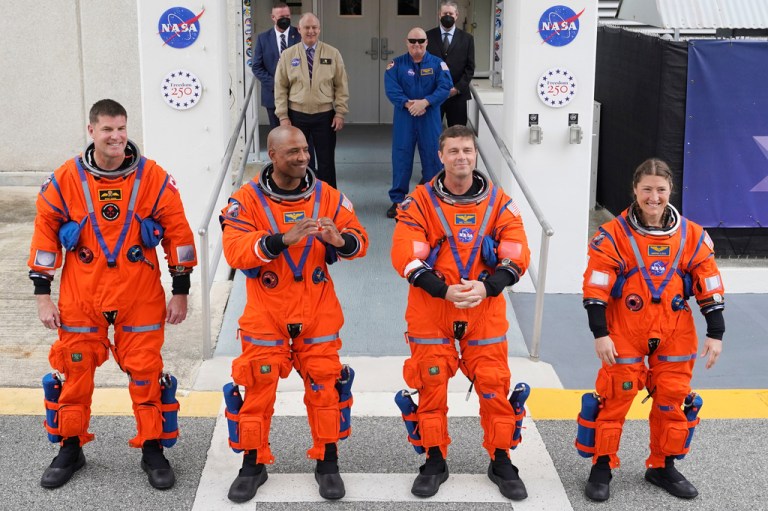 Artemis II crew standing in their space suits.