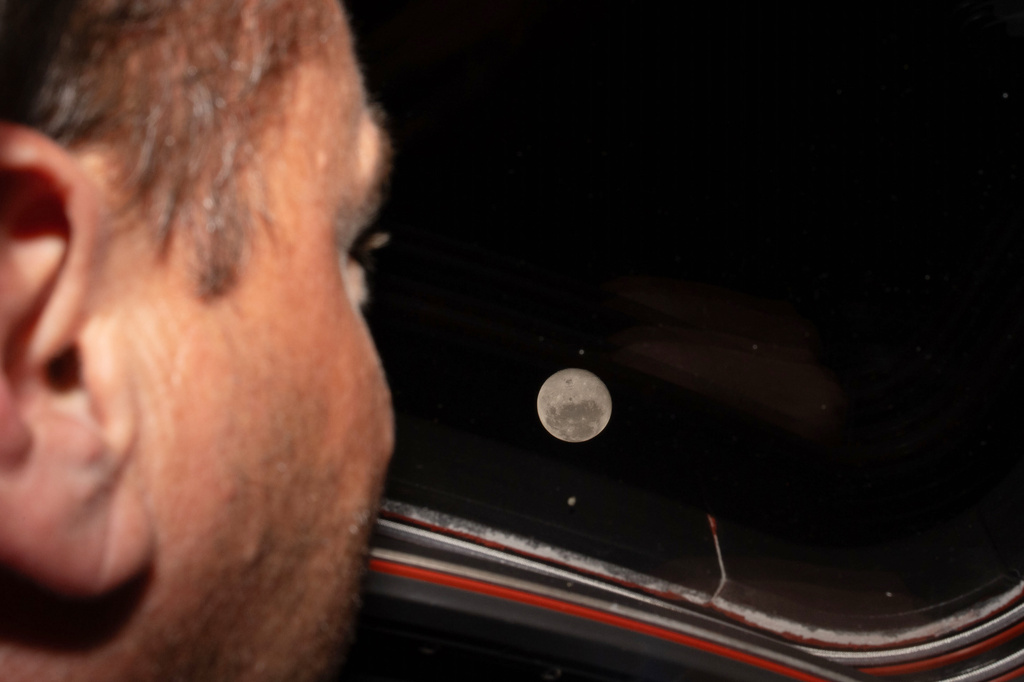 Artemis II commander and NASA astronaut Reid Wiseman looks out one of the Orion spacecraft's main cabin windows at the moon ahead of the crew's lunar flyby.