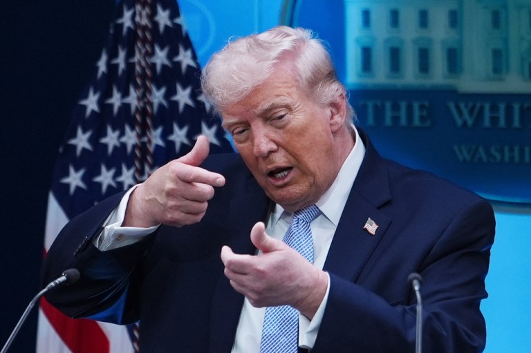 President Donald Trump pretends to aim a gun.