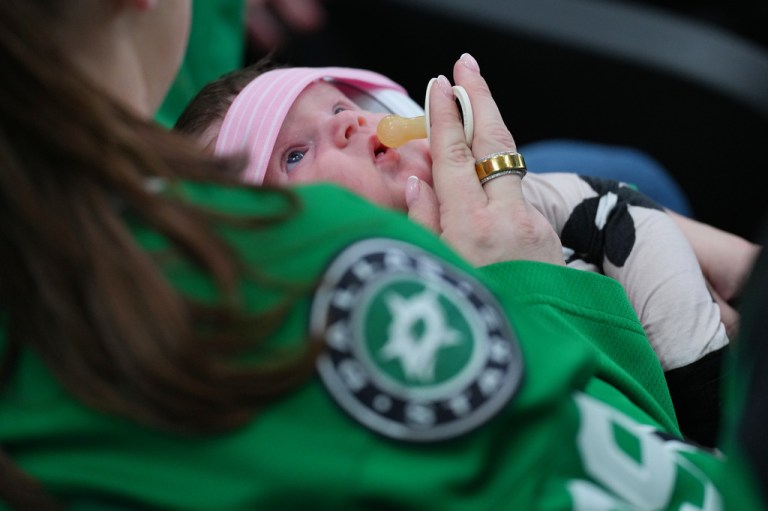 A person offers a pacifier to a baby during the third period of an NHL hockey game