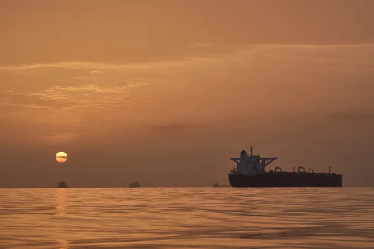 The sun rises behind tankers anchored in the Strait of Hormuz.