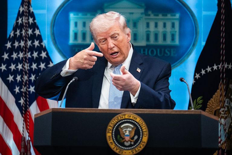 President Donald Trump mimics firing a gun during a news conference in the White House briefing room.