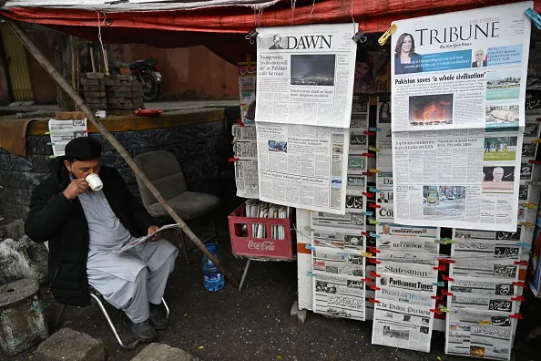 A vendor drinks tea as he reads a morning newspaper at a roadside stall in Islamabad on April 8, 2026.