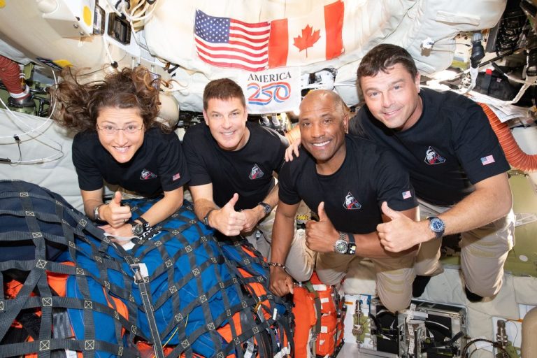 The Artemis II crew – from left, Mission Specialist Christina Koch, Mission Specialist Jeremy Hansen, Pilot Victor Glover, and Commander Reid Wiseman – pause for a group photo inside the Orion spacecraft on their way home.