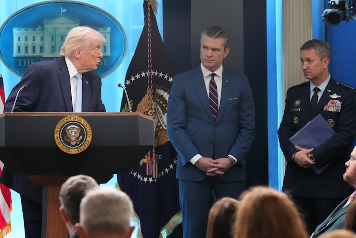President Donald Trump looks to Defense Secretary Pete Hegseth and Chairman of the Joint Chiefs of Staff Gen. Dan Caine as he speaks with reporters during a news conference in the James Brady Press Briefing Room at the White House, Monday, April 6, 2026, in Washington. (AP Photo/Mark Schiefelbein)