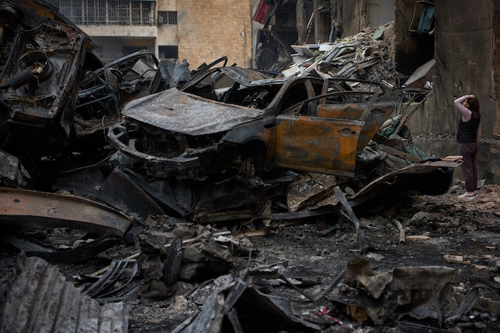 A resident checks damage to buildings as she walks near charred cars, at the site of Wednesday's Israeli airstrike, in Beirut, Lebanon, Friday, April 10, 2026. (AP Photo/Emilio Morenatti)