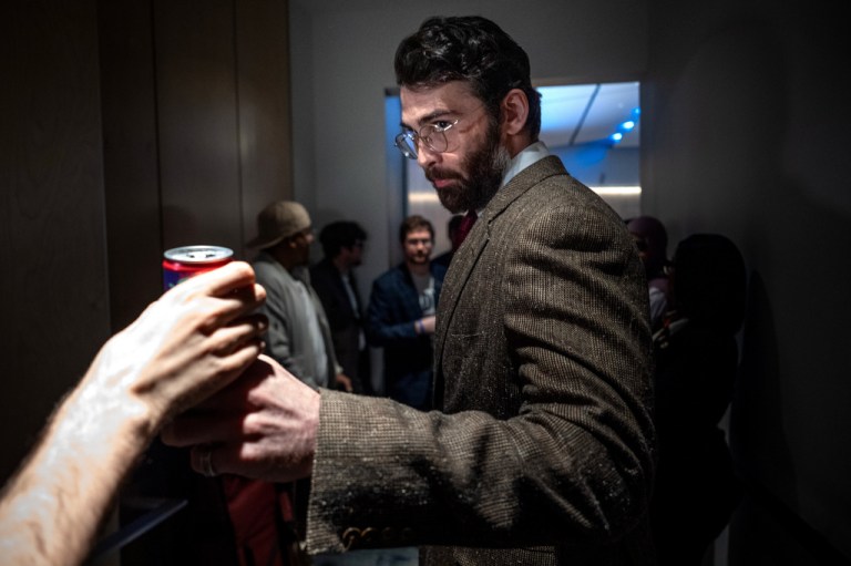 Streamer Hasan Piker hands his energy drink to producer Mauricio Miranda before going on stage to speak at a campaign event for Abdul El-Sayed, a progressive candidate in the Democratic primary for U.S. Senate in Michigan.