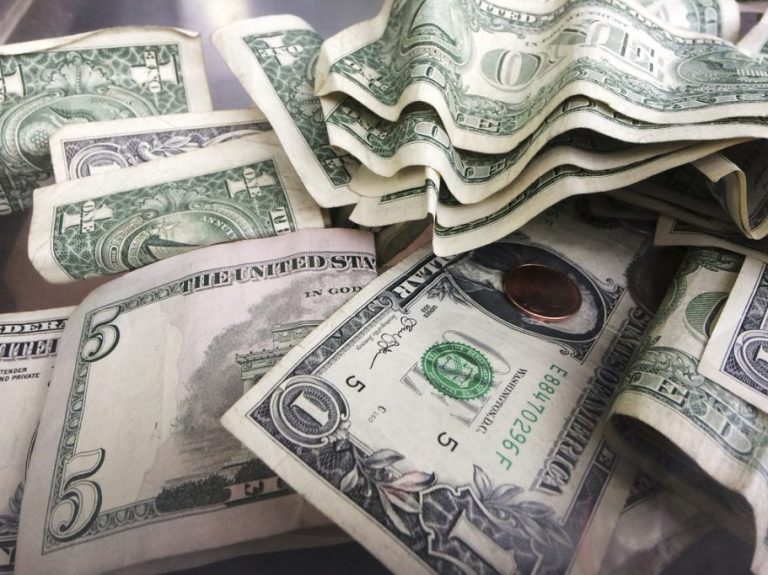 A tip jar contains $1 and $5 bills.