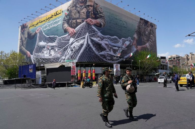 Two police officers walk in front of an anti-U.S. billboard in Tehran depicting the American aircraft into the Iranian armed forces fishing net with signs that read in Farsi: 