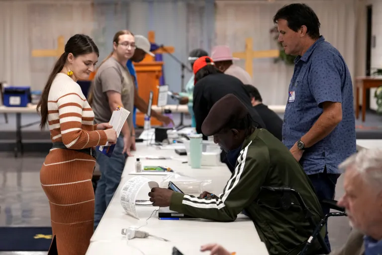 A poll worker, third from right, assists a voter, left, on Election Day.